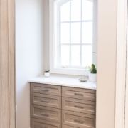A walk-in closet with two drawers and a window, designed with custom closet organization systems.