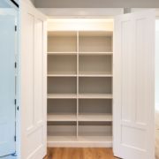 A white Custom Closet Design with open doors in a room.