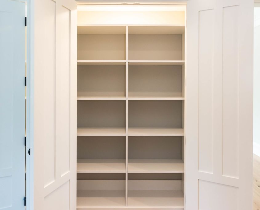 A white Custom Closet Design with open doors in a room.