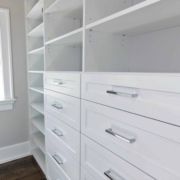 A white Custom Closet Design with drawers and a window.
