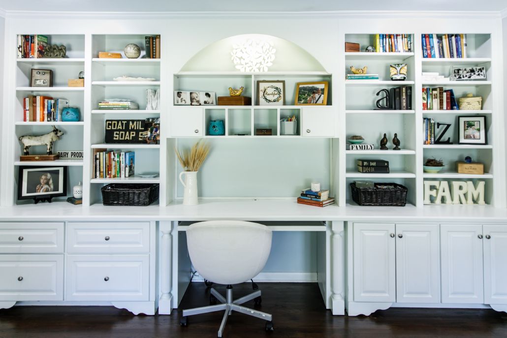 A white home office with bookshelves and a chair featuring organization systems.